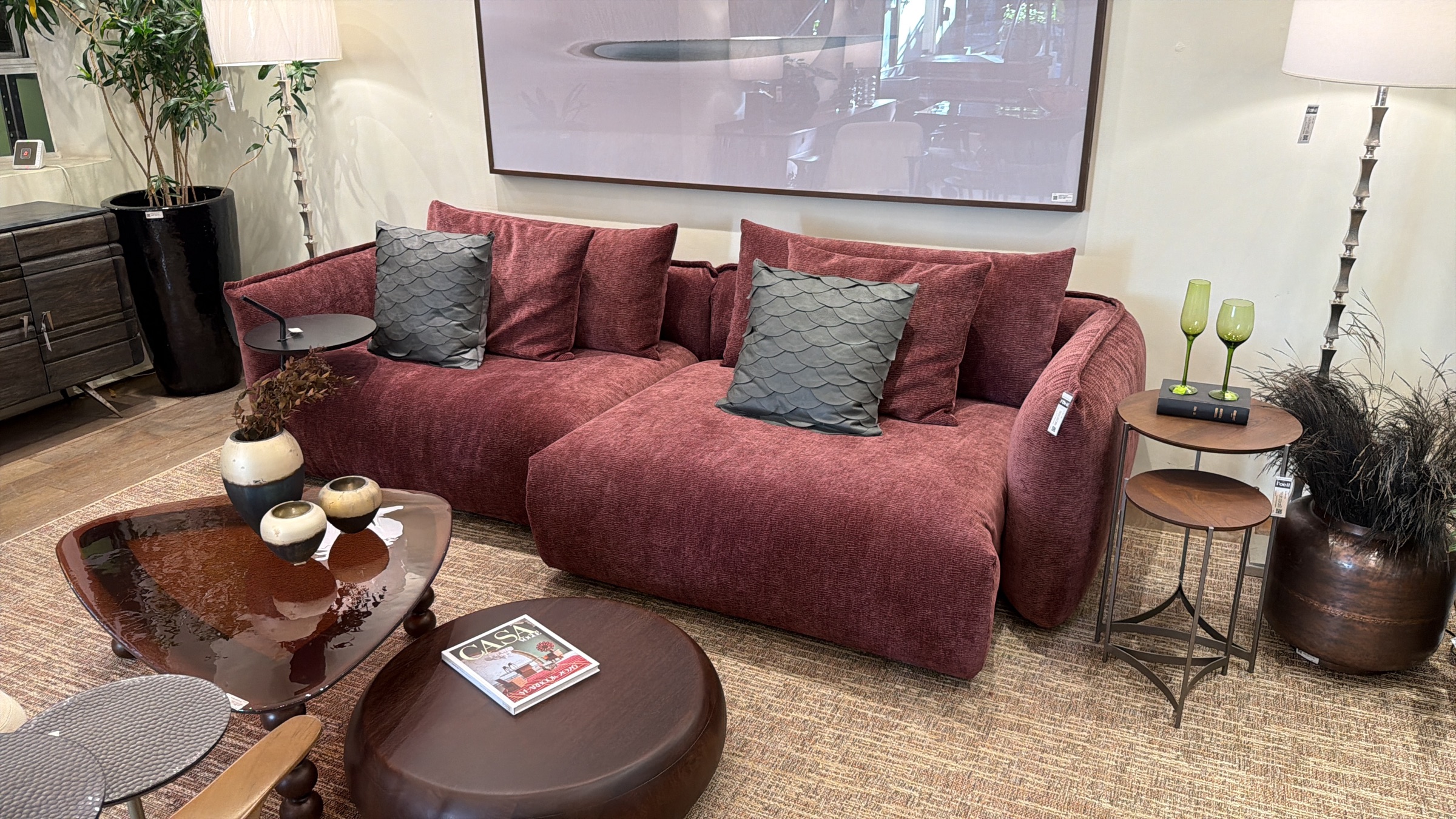 Composição de living com sofá bordô, mesas e objetos decorativos